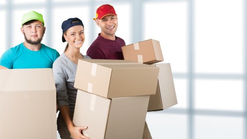 Furniture removals team handling heavy items in a Holland Park residential street